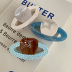 Three planet-shaped hair clips with rings and star embellishments, displayed on a book.