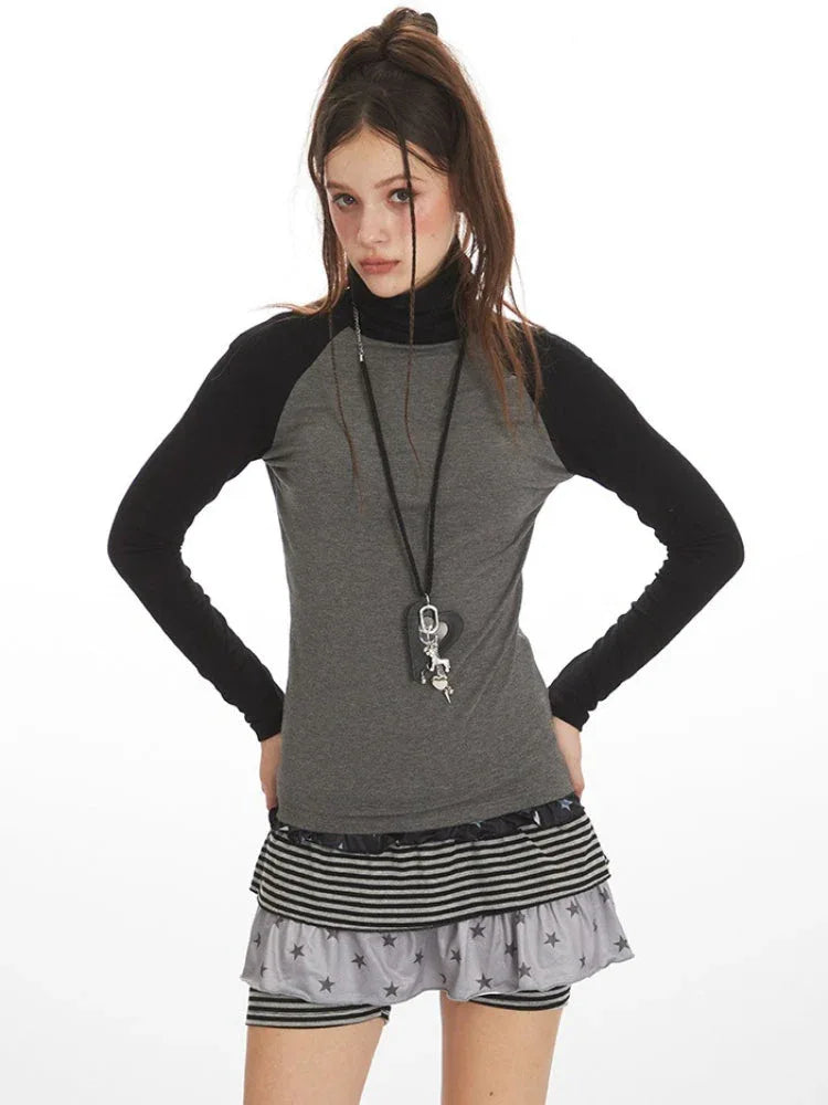Close-up of model wearing a gray and black long-sleeve turtleneck top with a layered skirt and necklace.