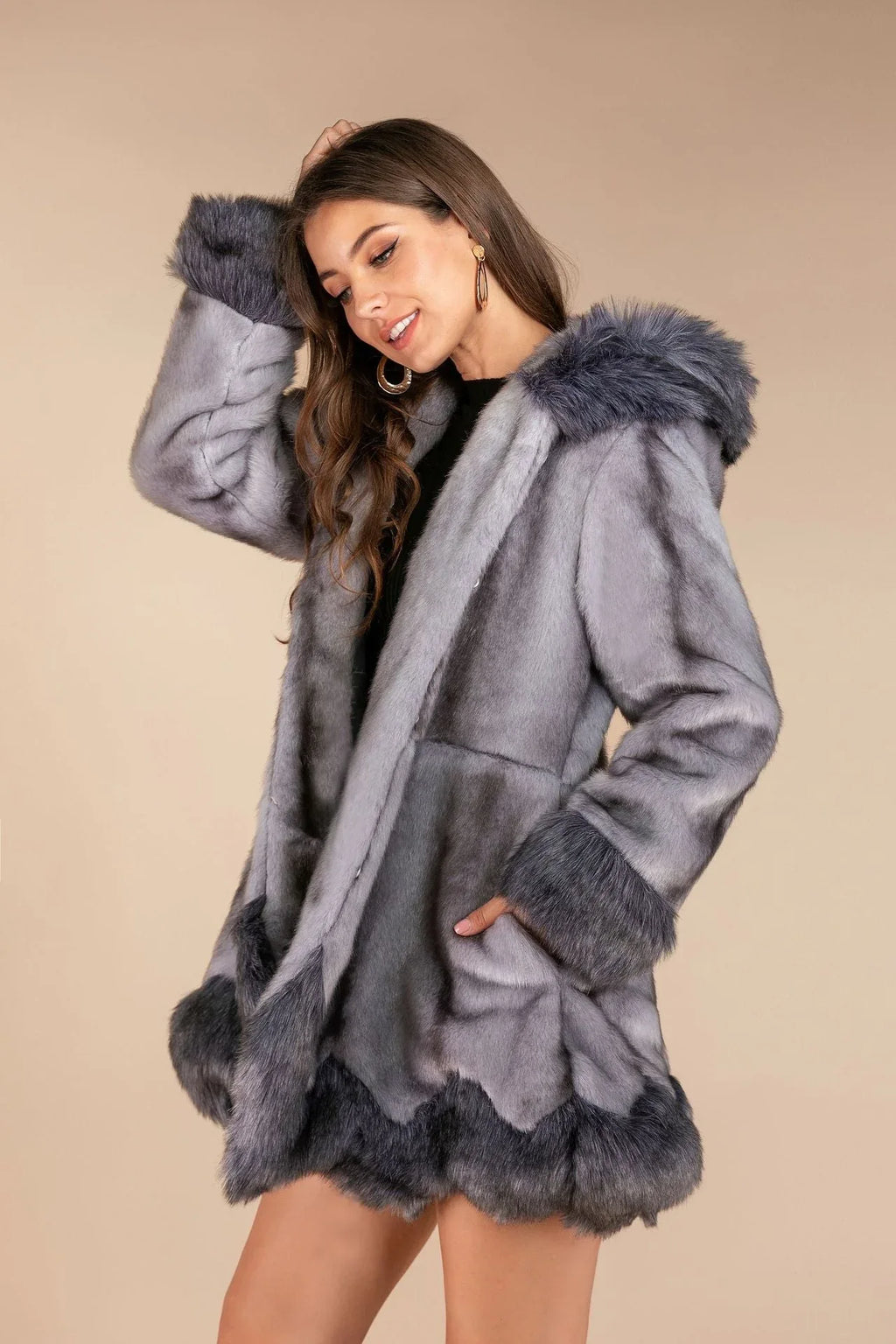 Woman wearing a grey faux fur coat and touching her hair