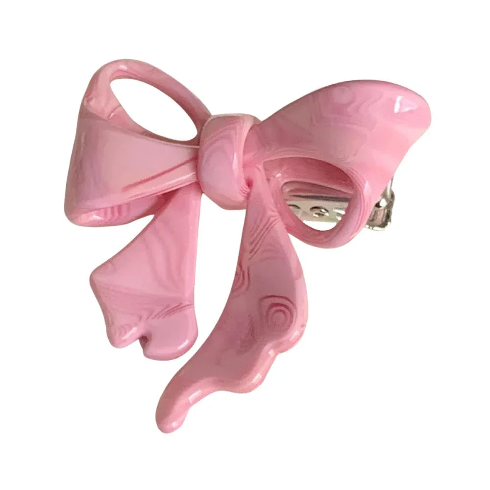 A pink bow-shaped hair clip with a marbled swirl pattern. Main image