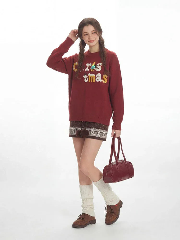 Woman in a burgundy Christmas sweater and patterned shorts, posing with a slight smile and one hand touching her hair. Secondary image