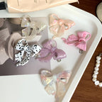 A collection of colorful bow-shaped hair clips arranged on a tray.