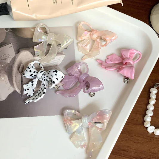 A collection of colorful bow-shaped hair clips arranged on a tray.