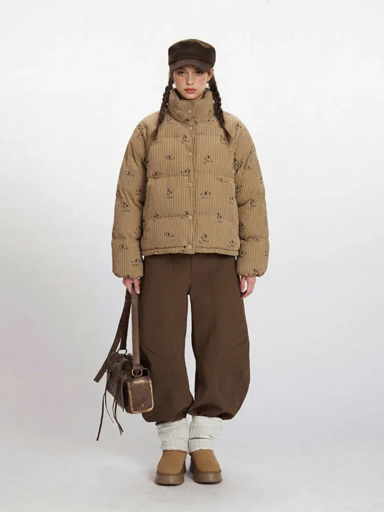 Woman wearing a tan corduroy puffer jacket with a repeating dog print, brown wide-leg pants, and a brown cap.