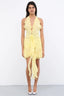 A woman wearing a yellow ruffled halter mini dress with ruching and a flower accent