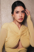 Close-up of a woman wearing a yellow ruched jersey top with a twisted front and plunging neckline
