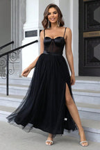 Woman in a black tulle maxi dress with a corset bodice and spaghetti straps.