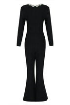 Rear view of a black velvet jumpsuit with long sleeves and flared legs.