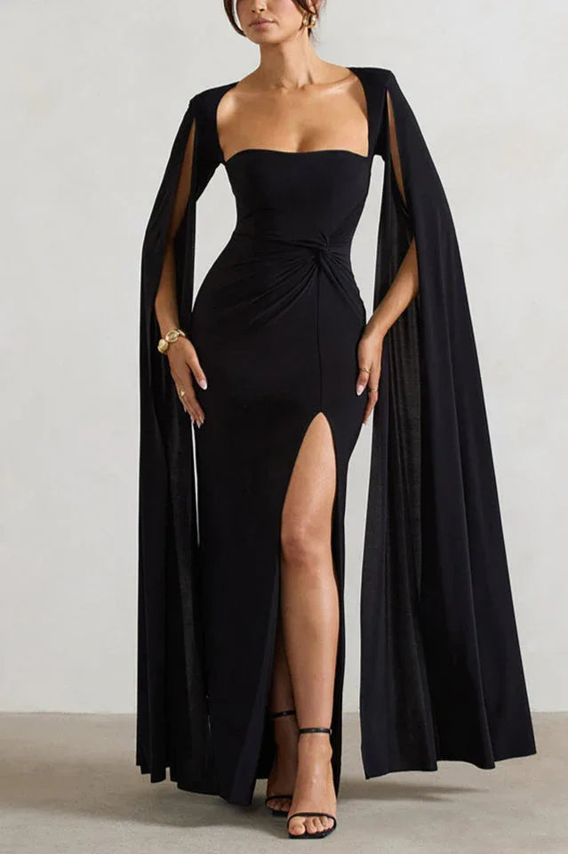 Woman wearing a floor-length black gown with a sweetheart neckline, cape sleeves, and a high leg slit.