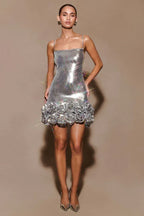 Full-length shot of a model in a silver sequin mini dress with a floral hem, paired with metallic heels.