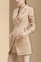 Side view of a woman in a beige blazer dress, showcasing the asymmetrical skirt.