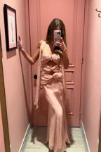 Woman taking a mirror selfie in a pale pink halter neck maxi dress with cut-out details and a mermaid hemline.