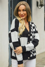 Woman in a black and white checkerboard print cropped cardigan, smiling.