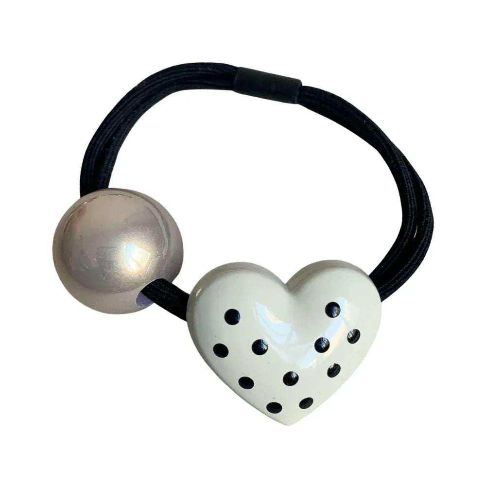 White heart-shaped hair tie with black polka dots and a silver bead