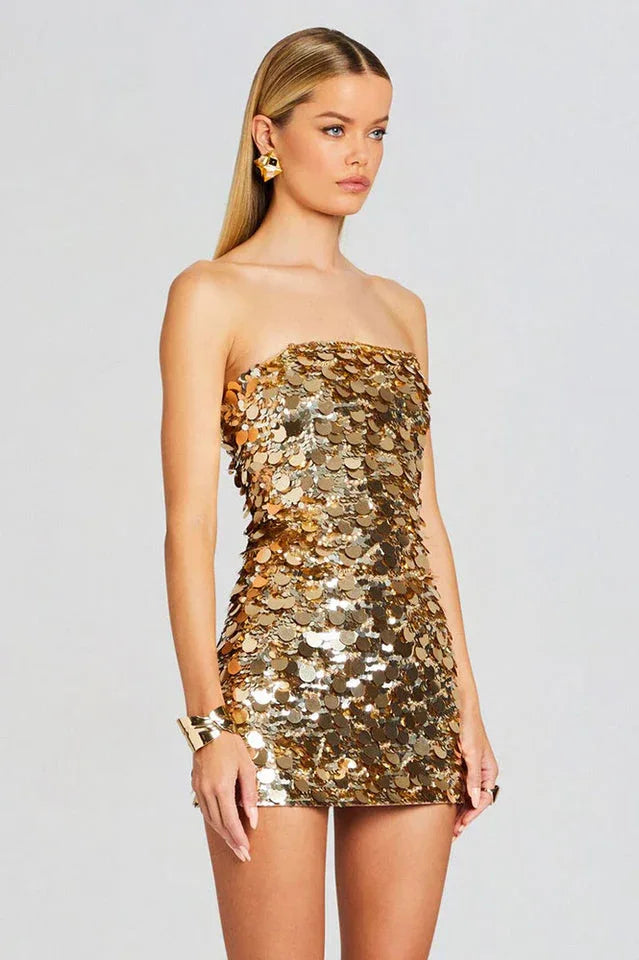 Woman wearing a gold sequined strapless mini dress, side view