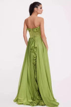 Woman in a green strapless satin gown with ruffled detailing, back view showing corset closure.