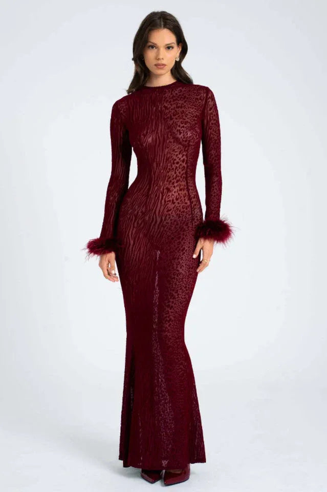 Woman wearing a long-sleeved, burgundy, animal print, sheer mesh dress with feathered cuffs and a mermaid hem, front view. Main image