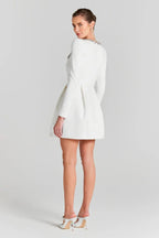 Back view of a white long-sleeve mini dress with a square neckline and a pleated A-line skirt.