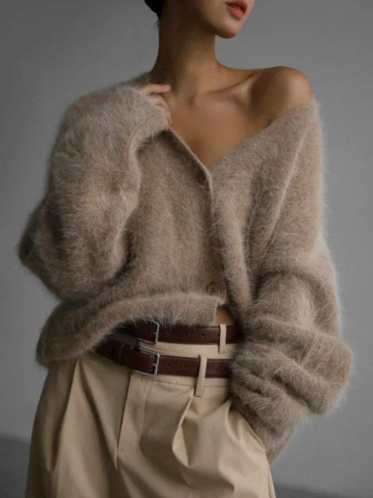 Model wearing a beige fuzzy V-neck button-up cardigan styled with light brown pants and a brown belt.