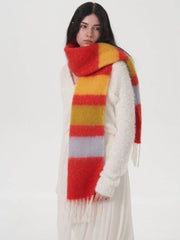 Full body shot of a woman wearing a white fuzzy sweater and a white pleated skirt, with a multi-colored striped scarf draped around her.