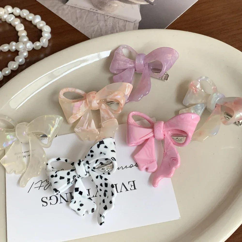 A close-up of various bow-shaped hair clips on a white tray.