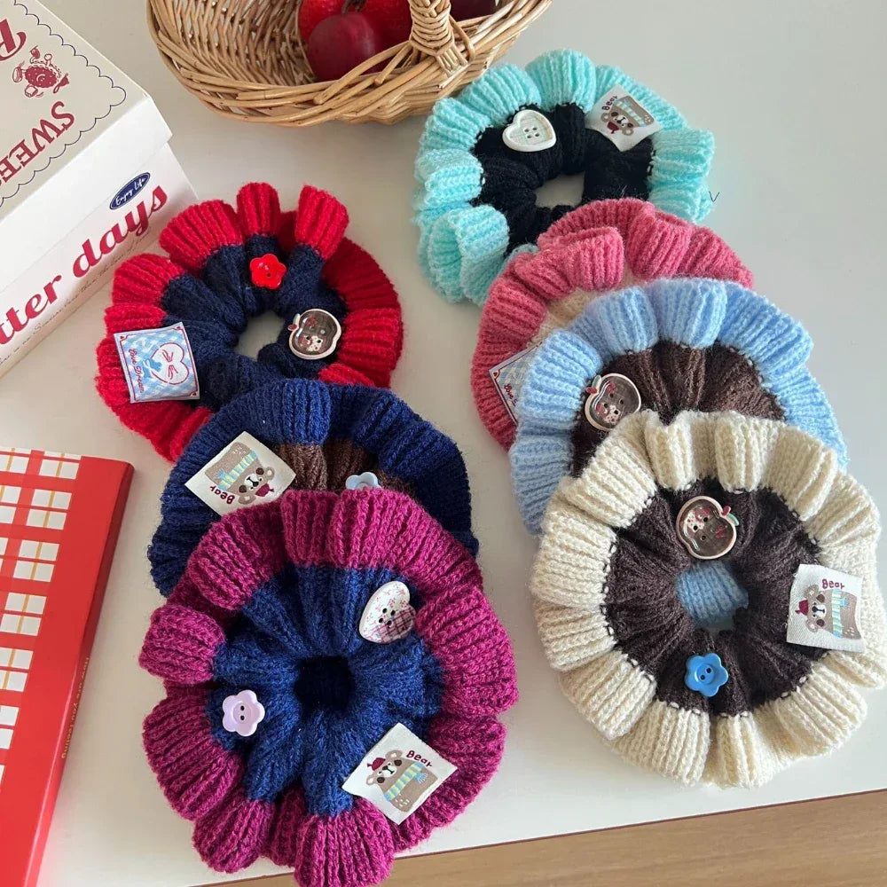 A collection of colorful knitted flower scrunchies arranged on a white surface.