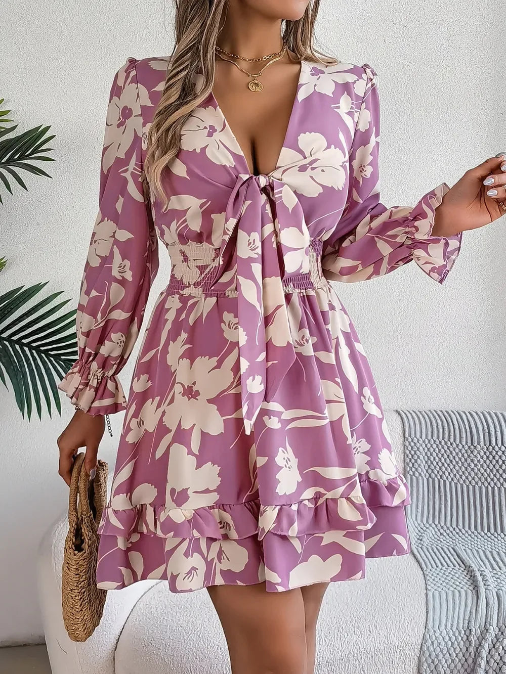 woman wearing a purple floral print mini dress with bishop sleeves and a tie front