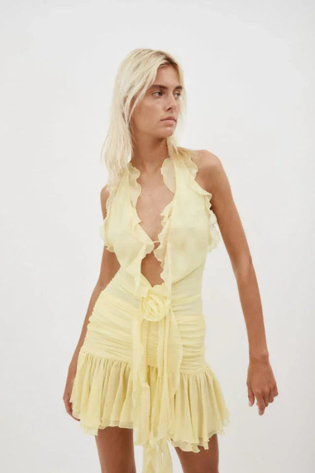 Close-up of a woman wearing a yellow ruffled halter mini dress Secondary image