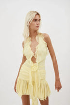 Close-up of a woman wearing a yellow ruffled halter mini dress