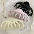 overhead view of three octopus claw hair clips in black, pink, and cream with pearls
