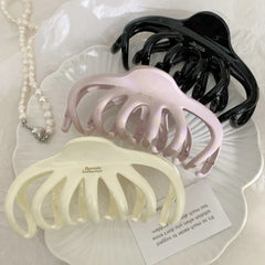 overhead view of three octopus claw hair clips in black, pink, and cream with pearls