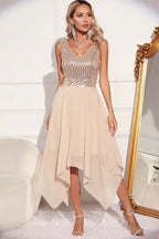 woman in a champagne sequined v-neck sleeveless formal dress with an asymmetrical hemline posing