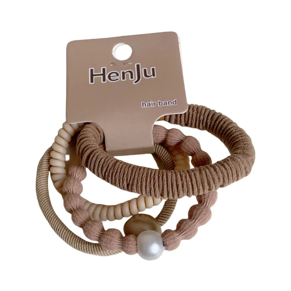 A set of three coiled hair ties in neutral tones, one with a pearl accent. Main image