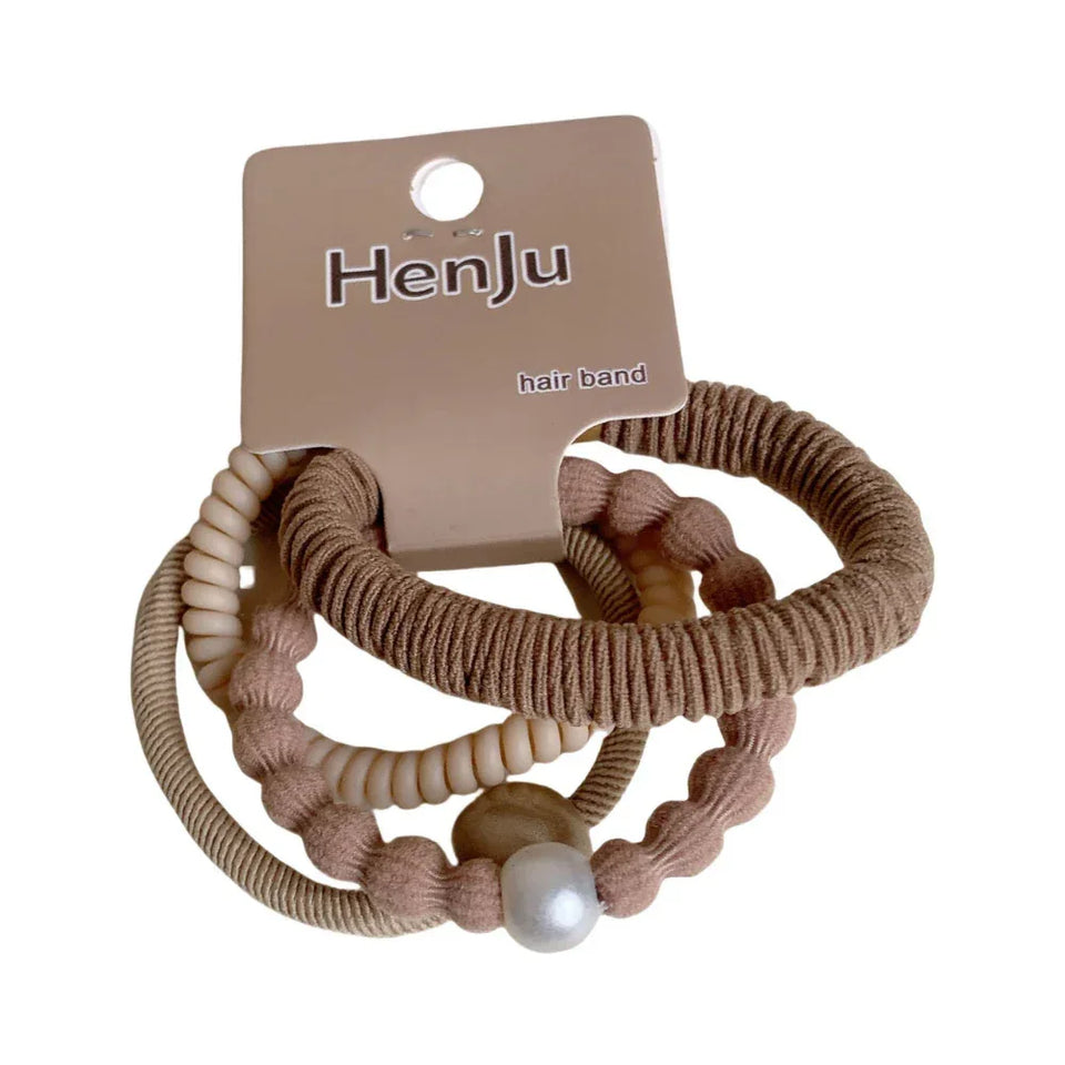 A set of three coiled hair ties in neutral tones, one with a pearl accent. Main image