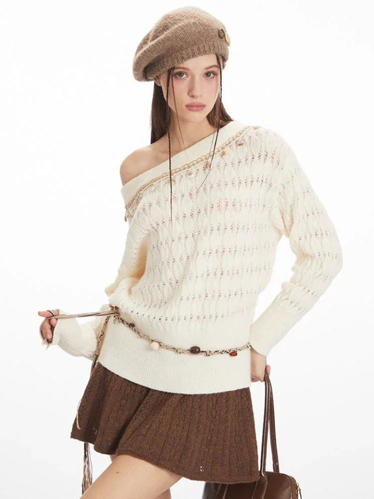 Close-up of a woman wearing a cream-colored off-the-shoulder knit sweater with a brown A-line skirt, holding a brown handbag.