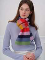 Woman wearing a blue sweater and a colorful striped scarf