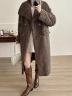 Woman wearing a long brown fuzzy fleece coat with a notched lapel and double-breasted closure, paired with a short skirt and brown boots.
