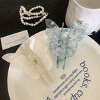 Two butterfly-shaped hair claw clips, one white and one blue with white marbling, displayed on a white plate with blue text.