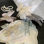 Several butterfly-shaped hair claw clips in pastel colors, including pink, blue, white, and purple, arranged on a tray and a white plate.