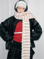 Model adjusting a cream and brown striped faux fur scarf.