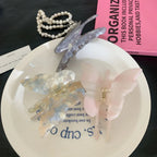 A selection of butterfly-shaped hair claw clips in pastel colors, including purple, pink, and marbled blue and white, displayed on a white plate.