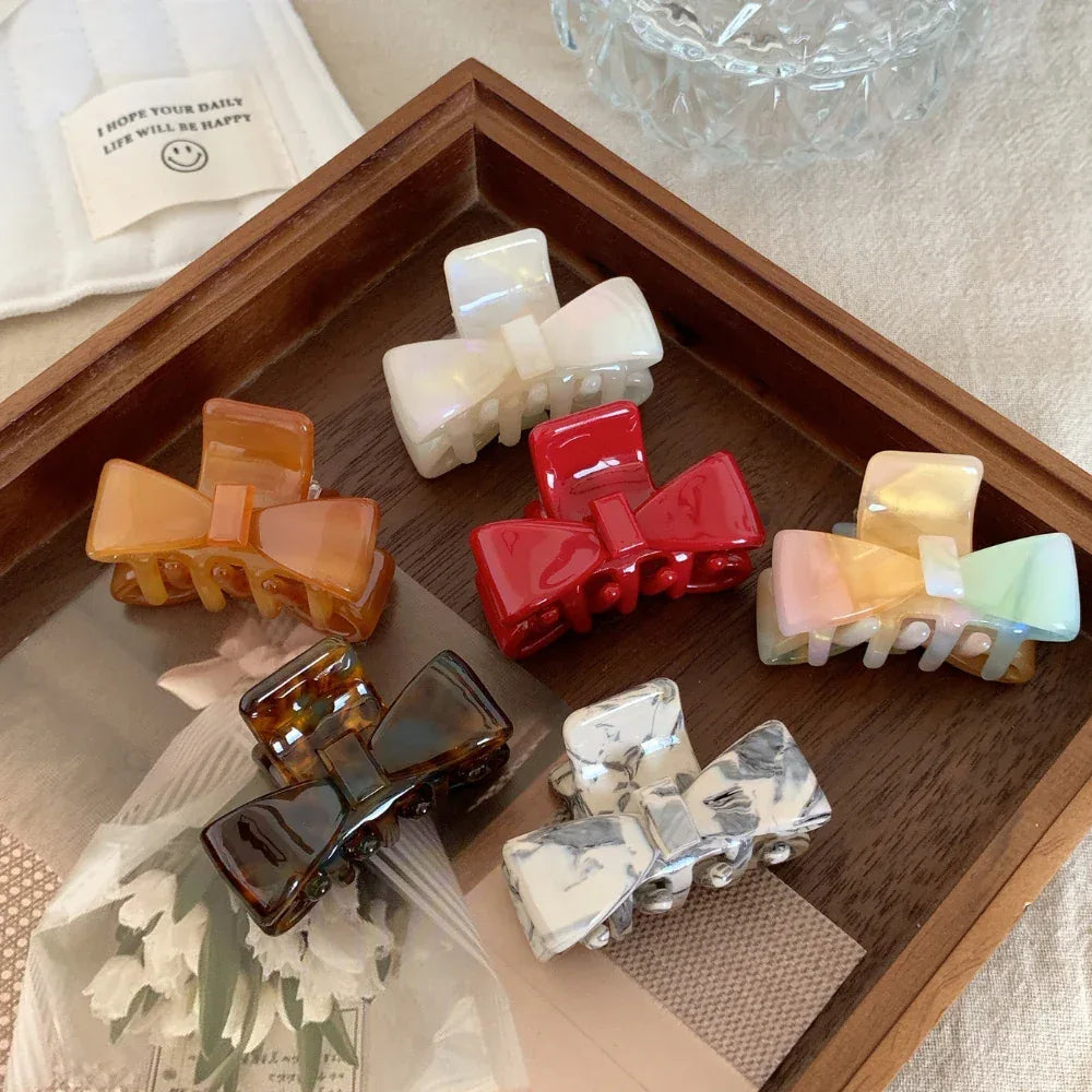 assortment of colorful bow claw clips arranged in a wooden tray