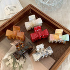 assortment of colorful bow claw clips arranged in a wooden tray