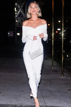woman in a white off-the-shoulder ruched maxi dress and white handbag