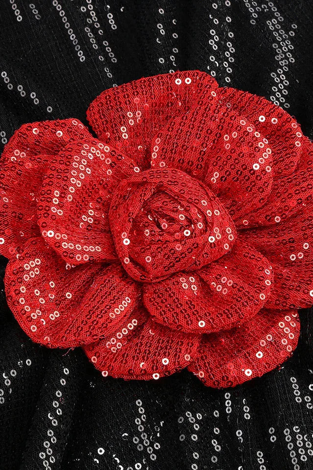 Close-up of a red sequined floral applique on a black sequined garment.