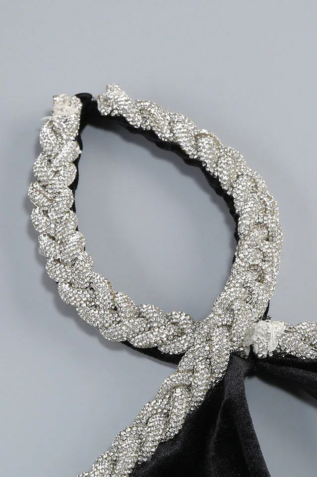 Close-up of the embellished halter neckline of a black velvet gown.