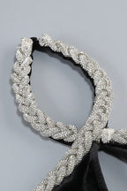 Close-up of the embellished halter neckline of a black velvet gown.