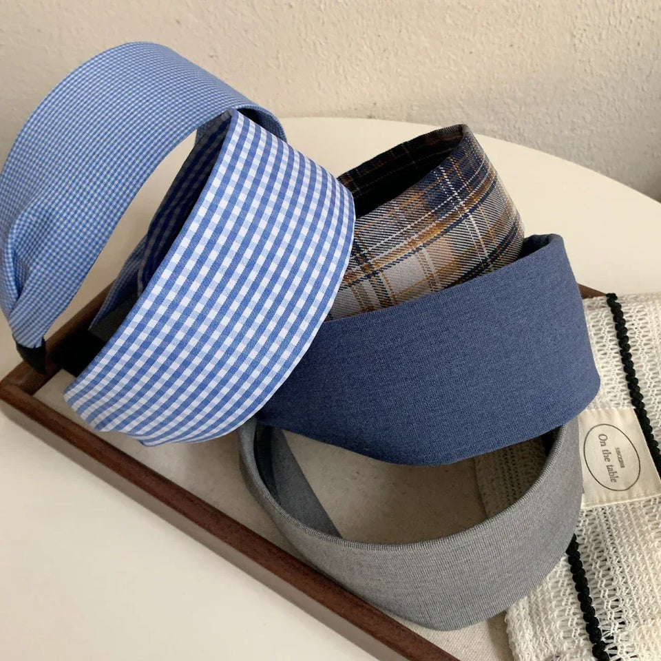 A stack of four headbands in different patterns: blue and white gingham, plaid, solid navy blue, and grey. Secondary image