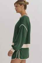 Side view of a woman in a green sweatshirt with cream trim