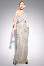 Model wearing a silver sequined one-shoulder draped gown with cut-out waist